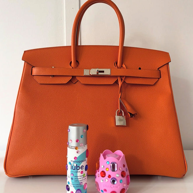 plusOne lube and vibrator beside an orange handbag